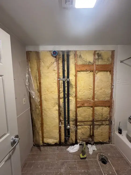 Wall stripped back to the studs around the plumbing stack