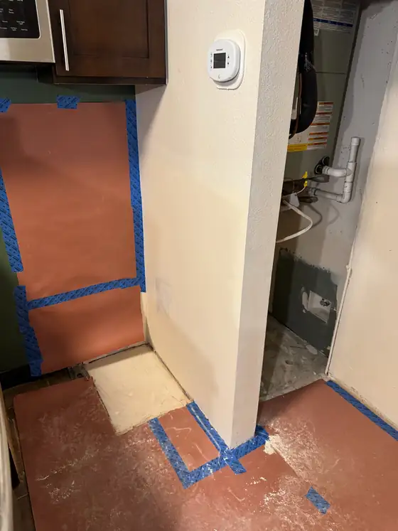 Wall patched and masked off beside the water heater closet