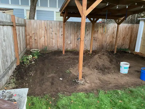 Excavated ground under the patio cover frame, ready for base material