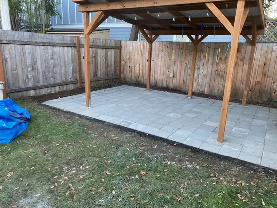 Finished paver patio under the cedar cover, along the fence line