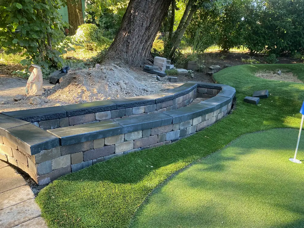 Curved segmental block retaining wall with a capped seat edge beside a putting green