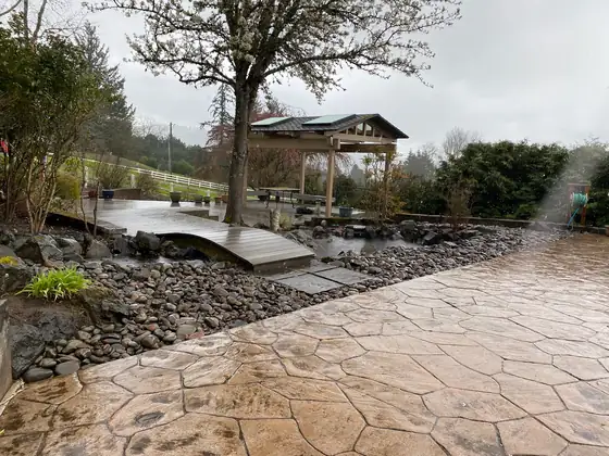 Finished pond and timber bridge with the stamped concrete patio alongside